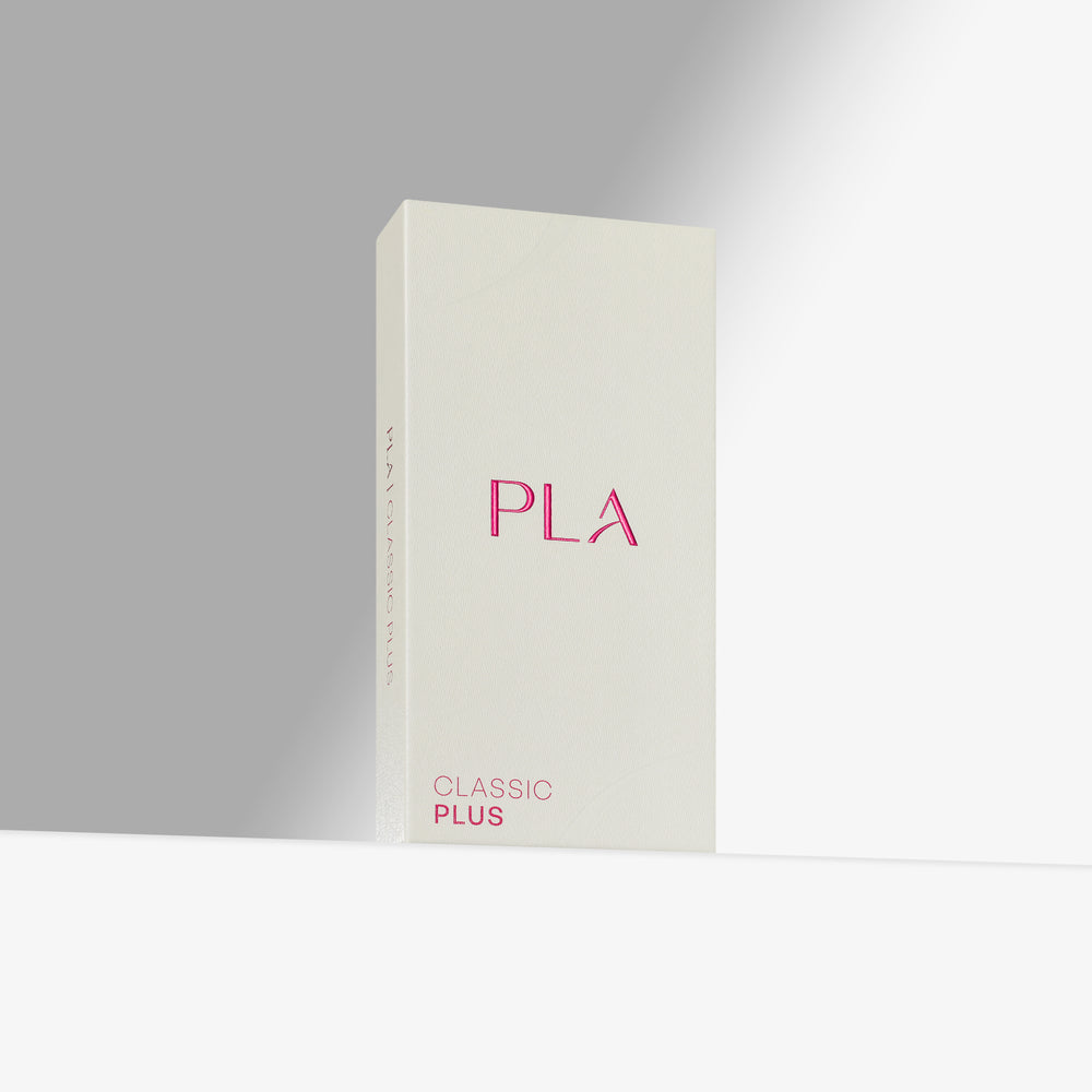 A tall, slim rectangular product box in off-white with pink lettering, standing upright on a white surface against a light gray background. The front reads 'PLA' in large pink letters and 'CLASSIC PLUS' near the bottom.