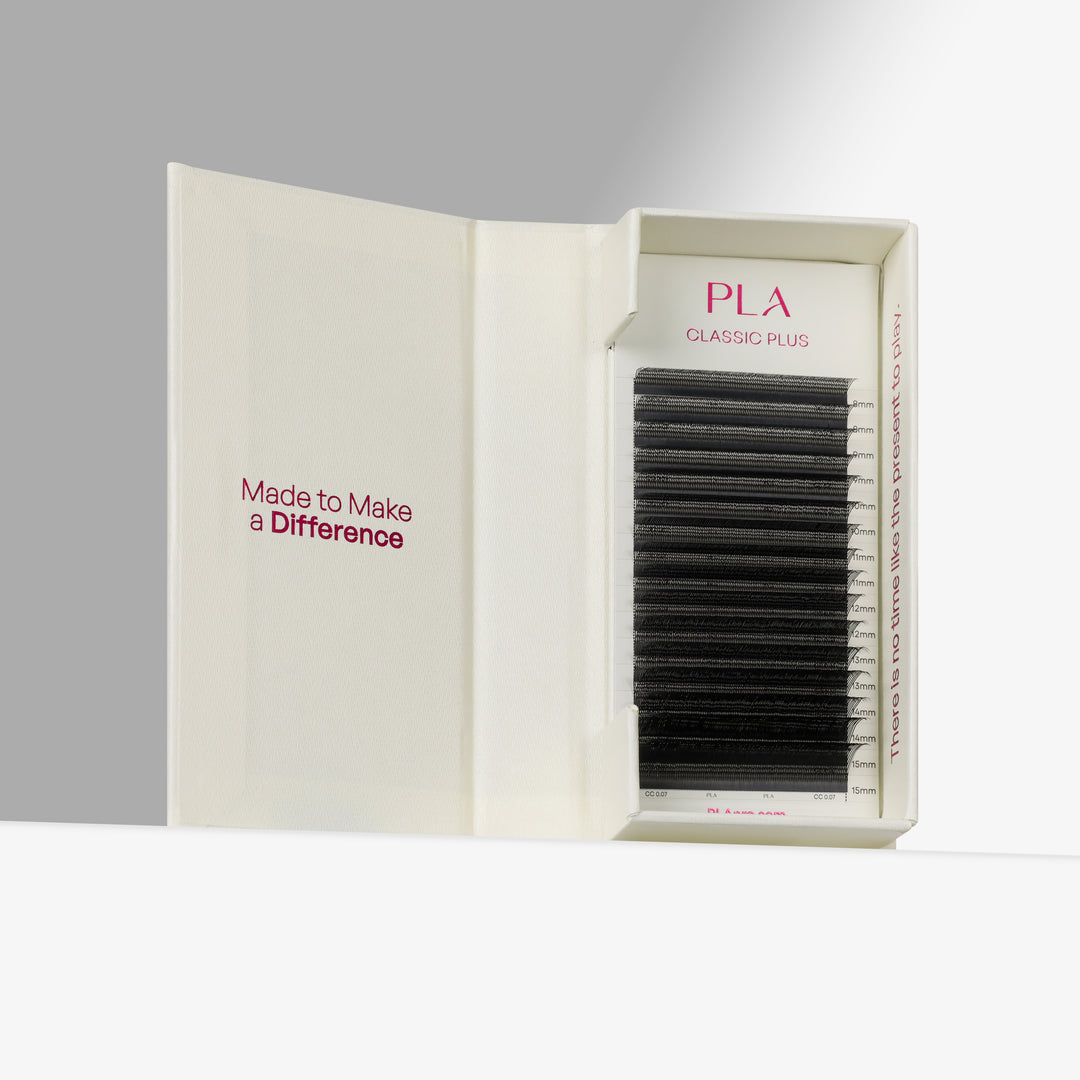 A boxed set of black eyelash extensions displayed in an open cream-colored case. The inside lid reads &
