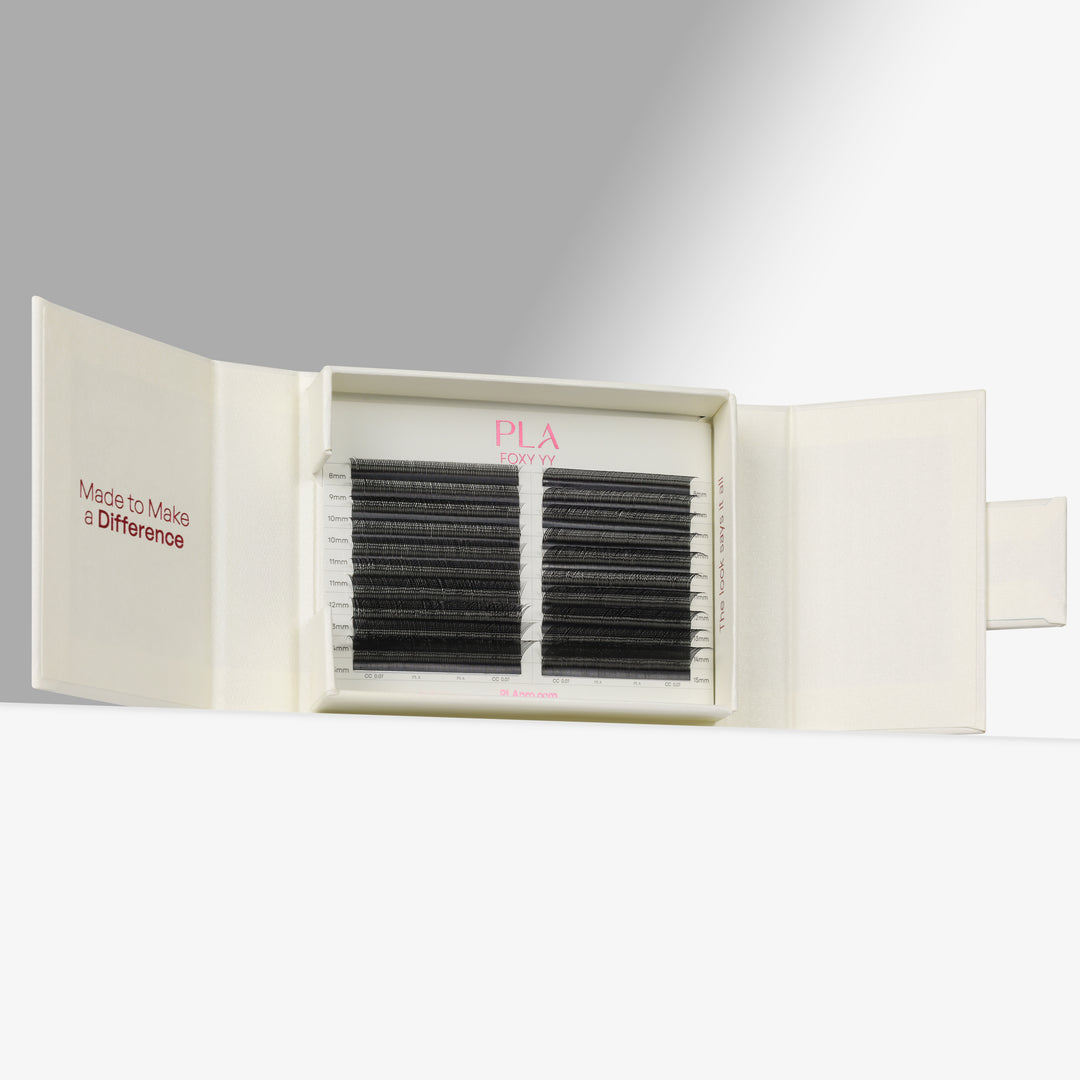 PLA Eyelash Extensions shown in their cream-colored packaging, with one side of the box closed displaying the pink PLA logo and the other side open to reveal two rows of black synthetic eyelash fibers.