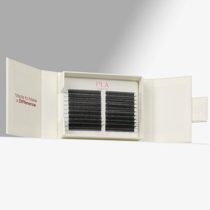 PLA Eyelash Extensions shown in their cream-colored packaging, with one side of the box closed displaying the pink PLA logo and the other side open to reveal two rows of black synthetic eyelash fibers.