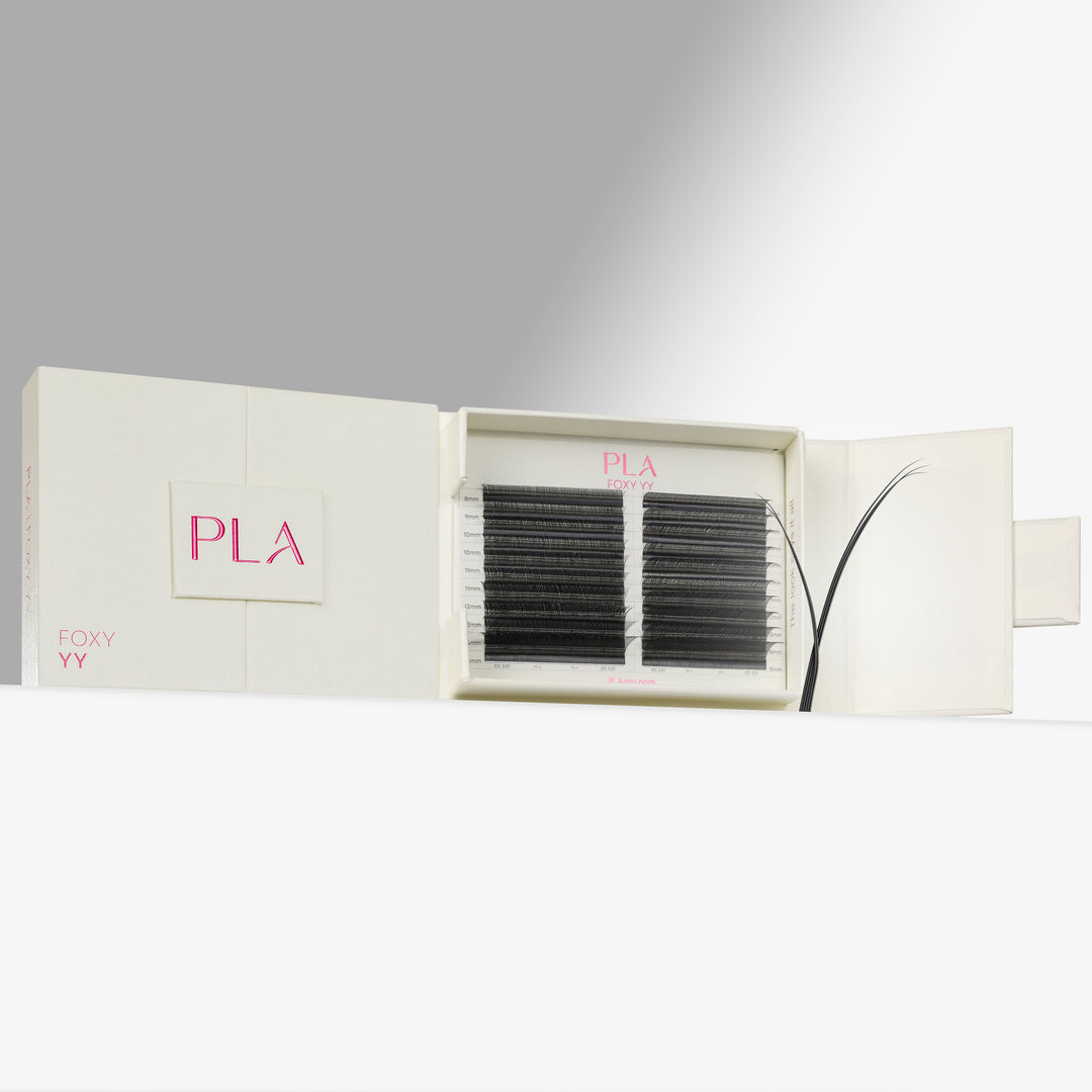PLA Eyelash Extensions shown in their cream-colored packaging, with one side of the box closed displaying the pink PLA logo and the other side open to reveal two rows of black synthetic eyebrow fibers.