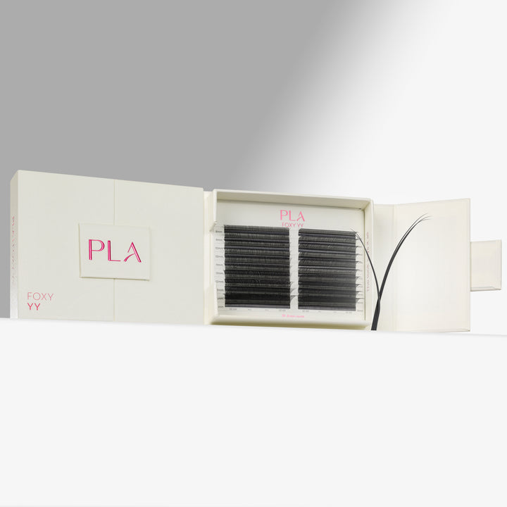 PLA Eyelash Extensions shown in their cream-colored packaging, with one side of the box closed displaying the pink PLA logo and the other side open to reveal two rows of black synthetic eyebrow fibers.