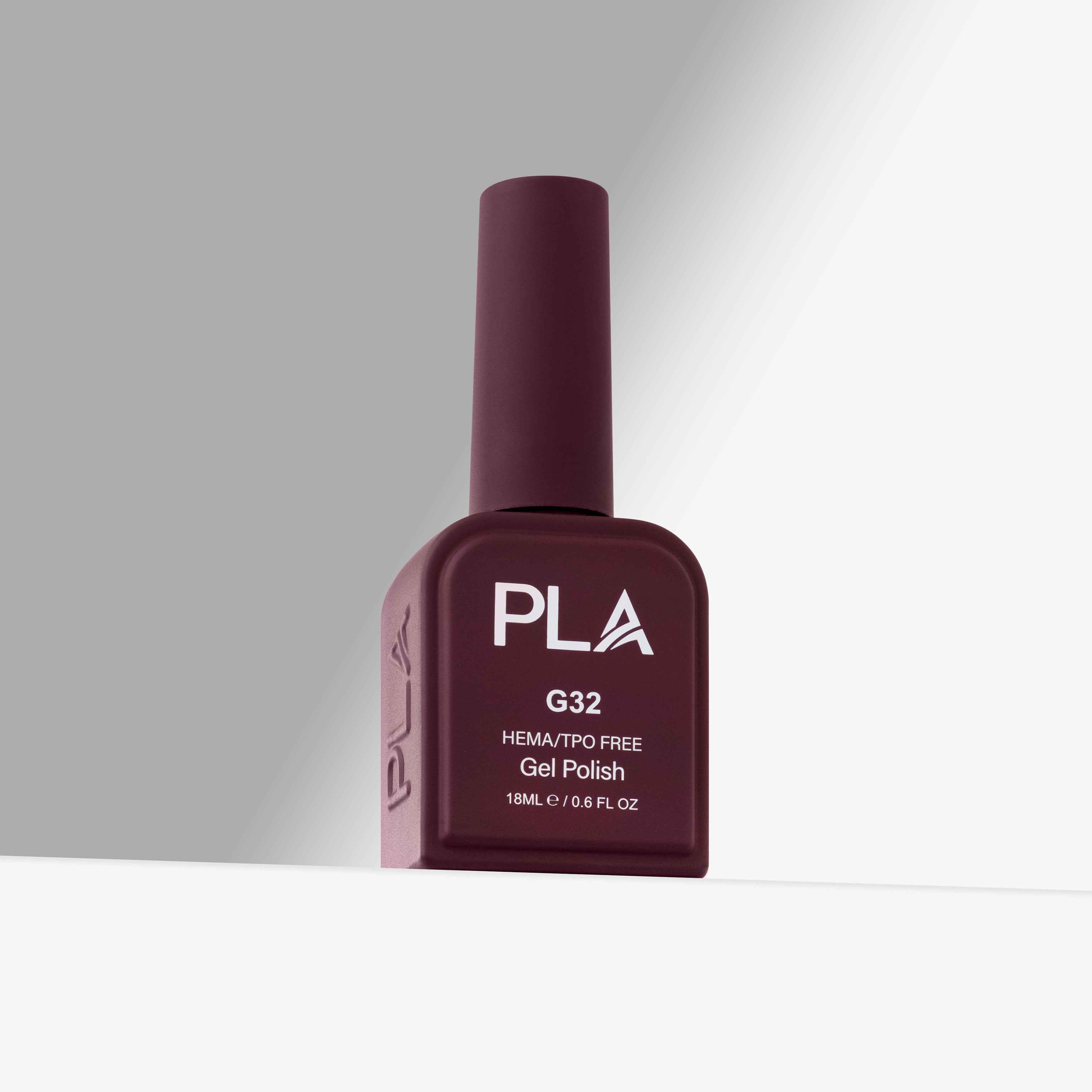 A bottle of PLA G32 HEMA/TPO Free Gel Polish in a deep burgundy shade, standing upright on a white surface against a gray background.