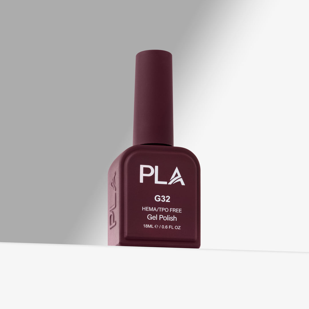 A bottle of PLA G32 HEMA/TPO Free Gel Polish in a deep burgundy shade, standing upright on a white surface against a gray background.