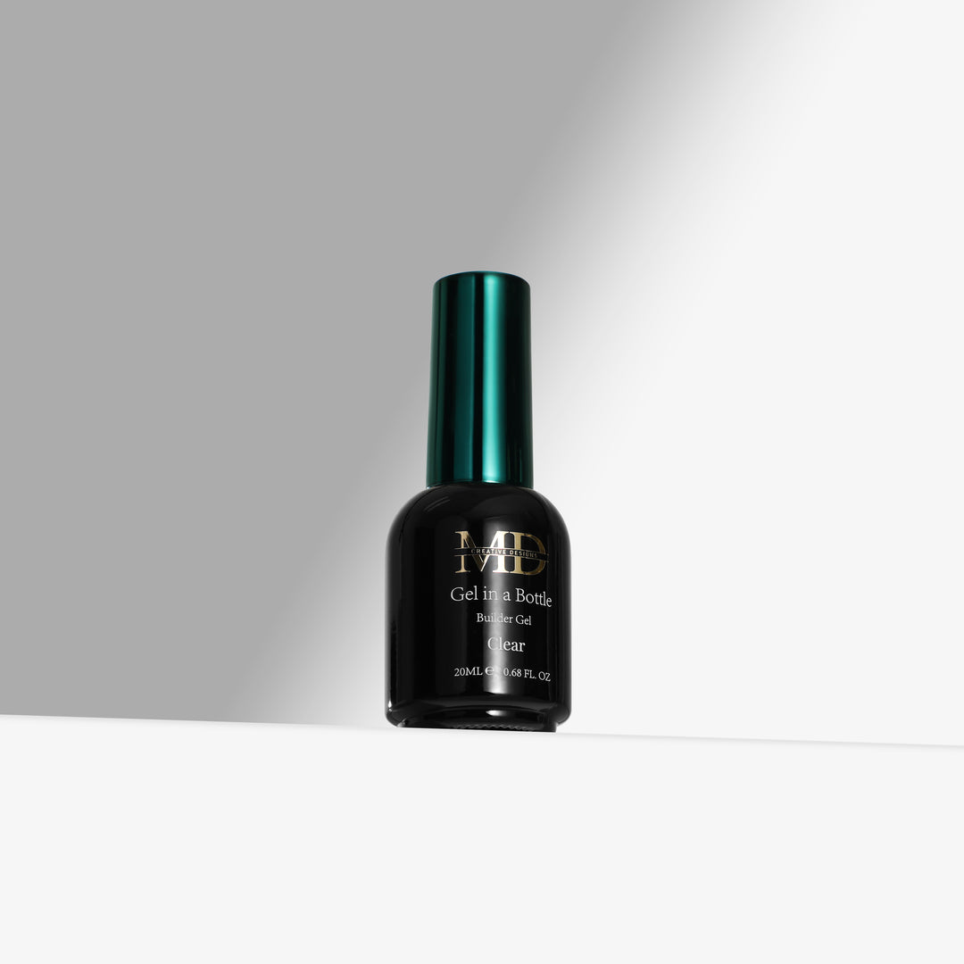 A bottle of MD Gel In a Bottle in the shade Clear, featuring a black bottle and a metallic dark green cap, set against a clean white and gray background.