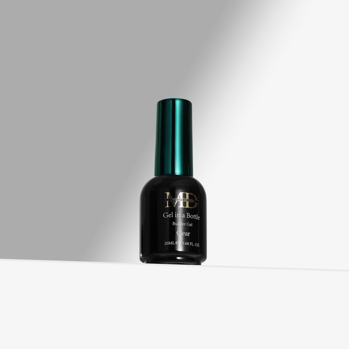 A bottle of MD Gel In a Bottle in the shade Clear, featuring a black bottle and a metallic dark green cap, set against a clean white and gray background.
