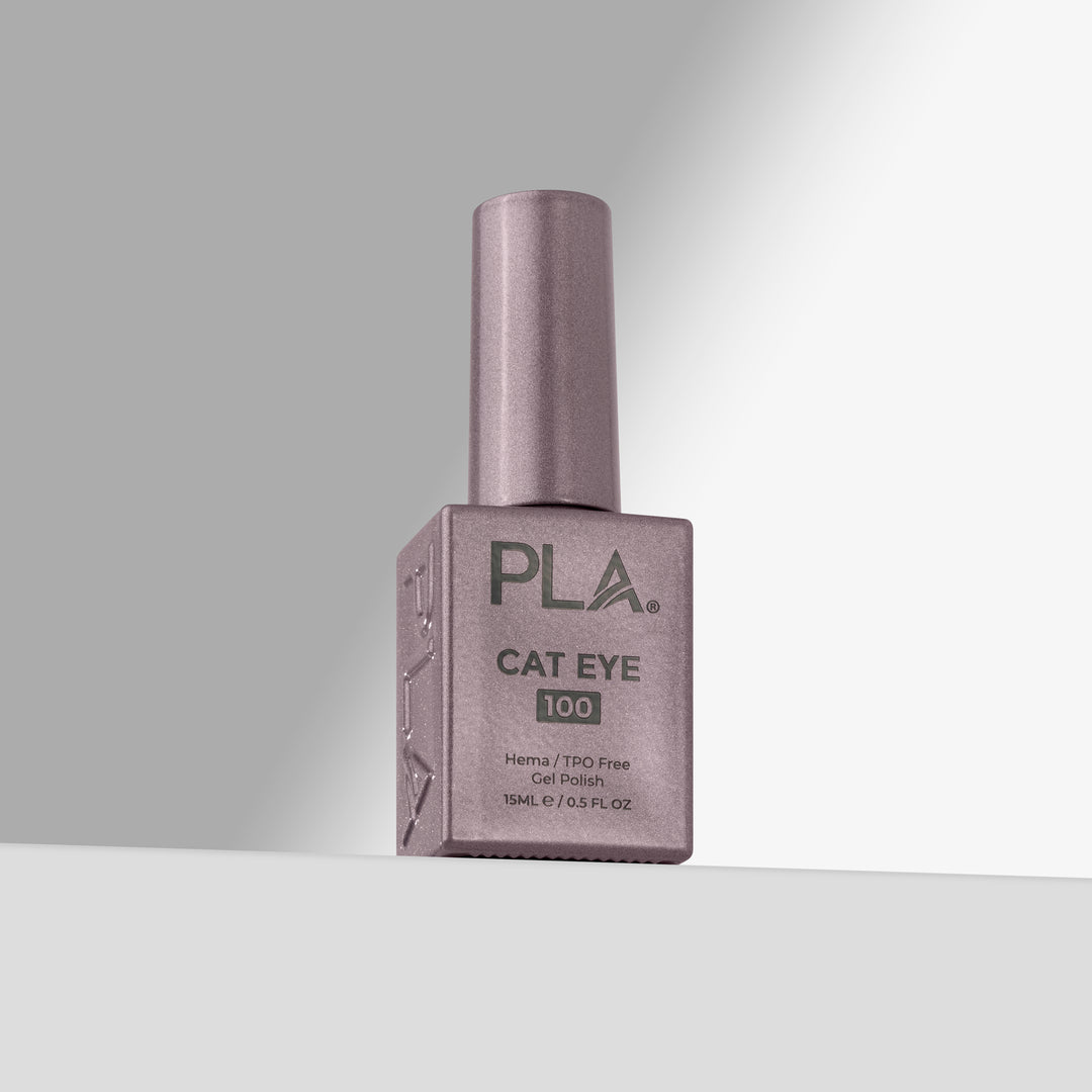 A bottle of PLA Cat Eye 100 nail polish in a lavender-purple shade, standing upright on a light gray surface against a gray background.