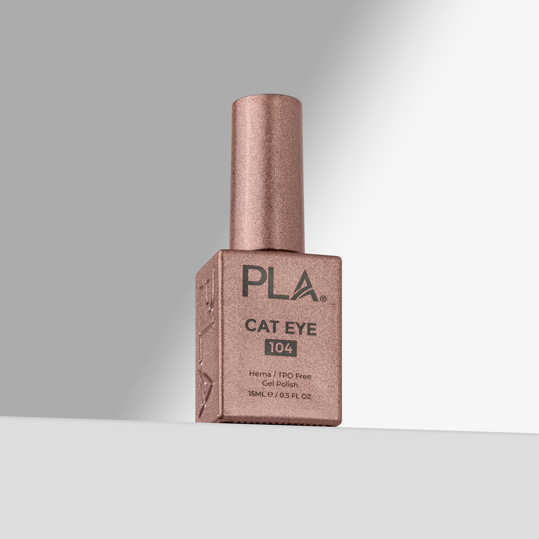 A bottle of PLA Cat Eye 104 gel nail polish in a sparkling rose gold color, standing upright on a light gray surface against a gray background.