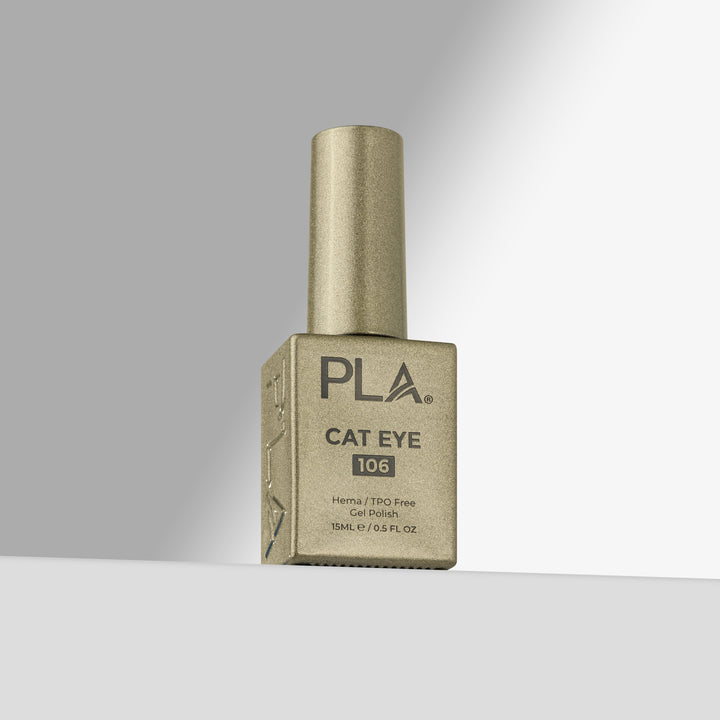 A bottle of PLA Cat Eye 106 gel nail polish in a gold shade, standing upright on a light gray surface against a gradient gray background.
