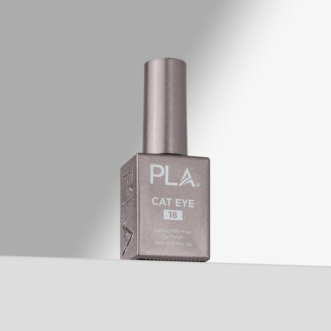 A bottle of PLA Cat Eye #18 nail polish in a silver-gray shade, standing on a light gray surface against a gray background with a soft spotlight effect.