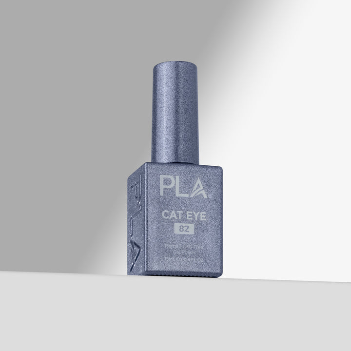 A single bottle of PLA Cat Eye gel nail polish in shade 82, featuring a shimmering slate blue-gray finish, set against a clean gray studio background 