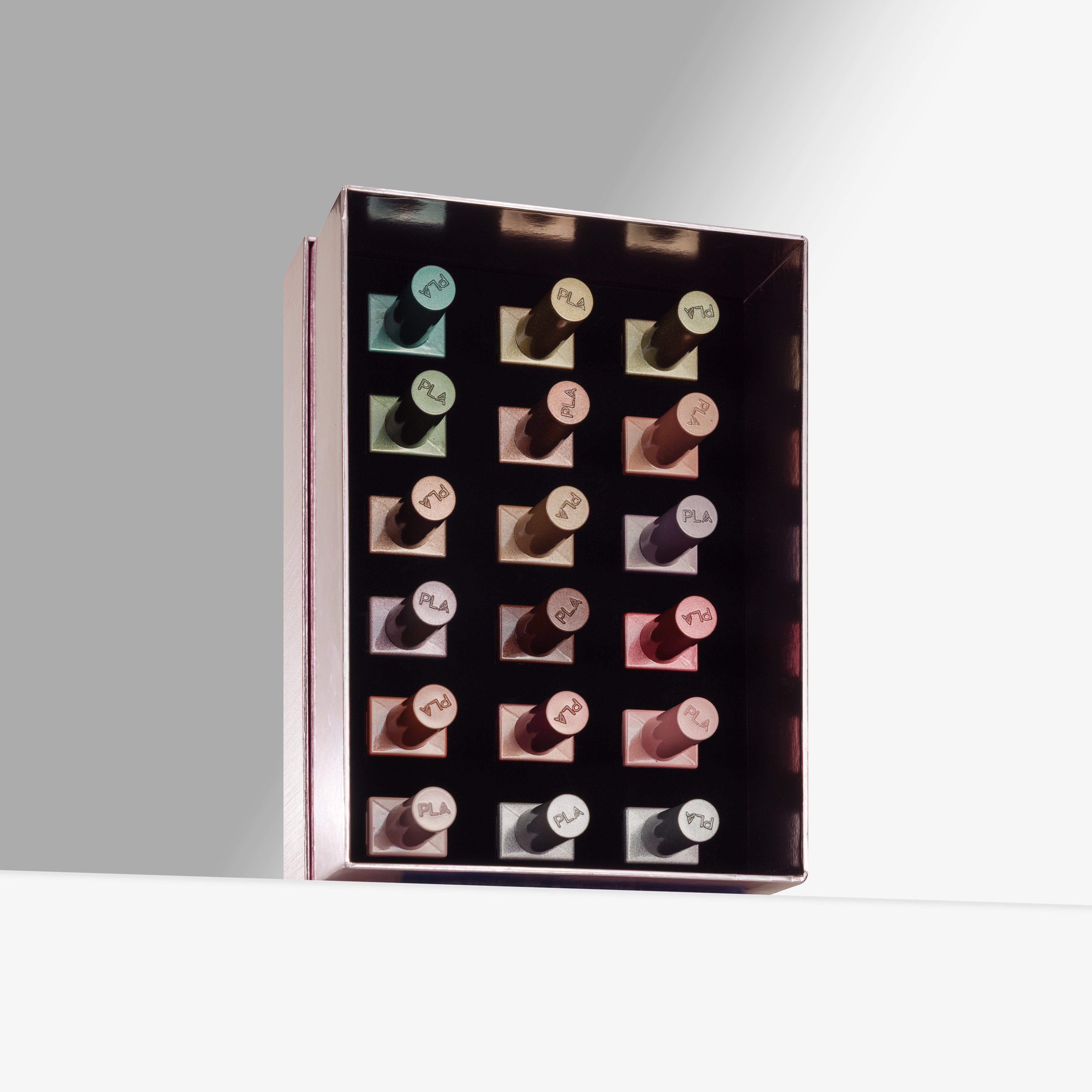 A rectangular light pink box with multiple cat eye gel nail polishes arranged in a grid, photographed on a clean light gray studio background.
